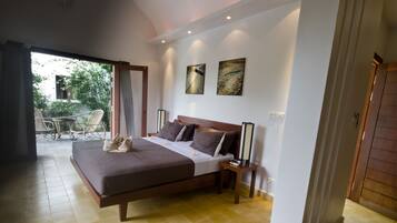 Quarto espaçoso com cama grande, mesa de cabeceira e vista para o pátio externo.