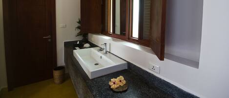 Un baño con un lavamanos blanco, una puerta de madera y un espejo encima.