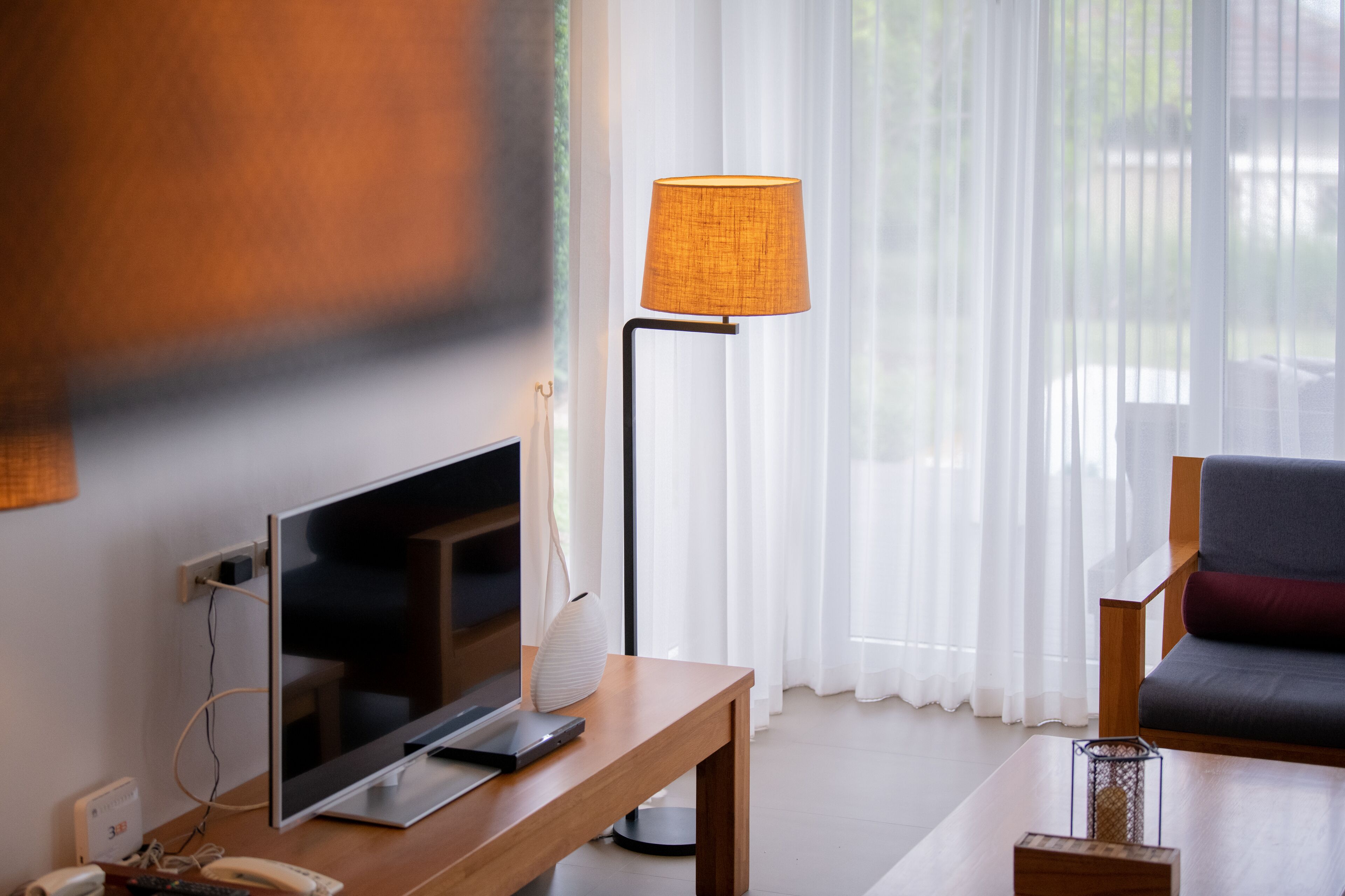 Un salon moderne avec un téléviseur à écran plat, une table basse en bois, un lampadaire et un canapé.