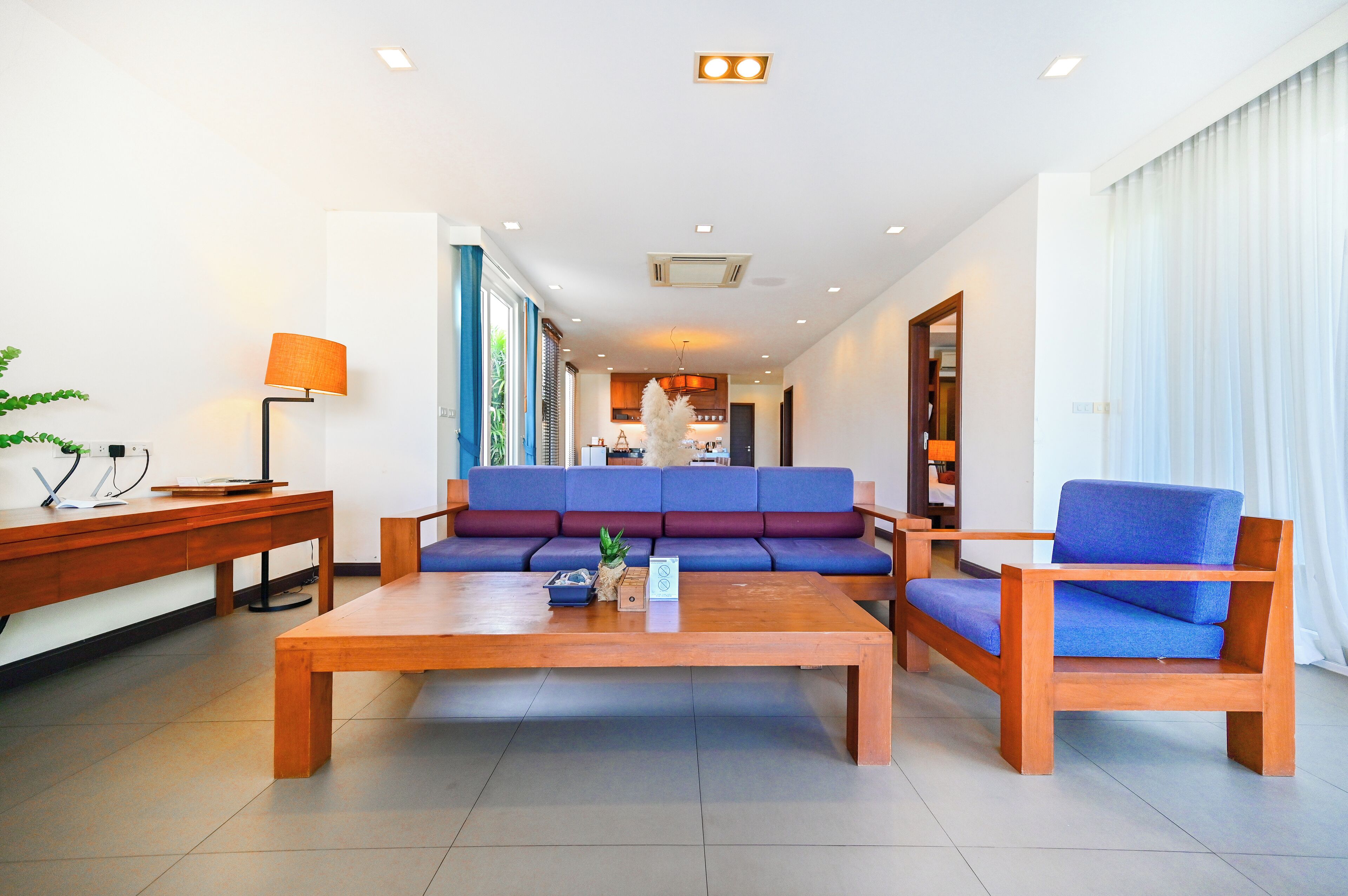 A modern hotel lobby with a wooden coffee table, a blue sofa, and a wooden armchair.
