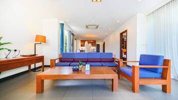 A modern hotel lobby with a wooden coffee table, a blue sofa, and a wooden armchair.