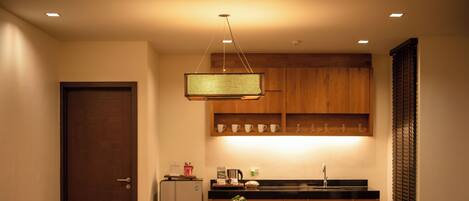 A compact kitchen with wooden cabinets, a dining table with chairs, and a hanging light fixture.