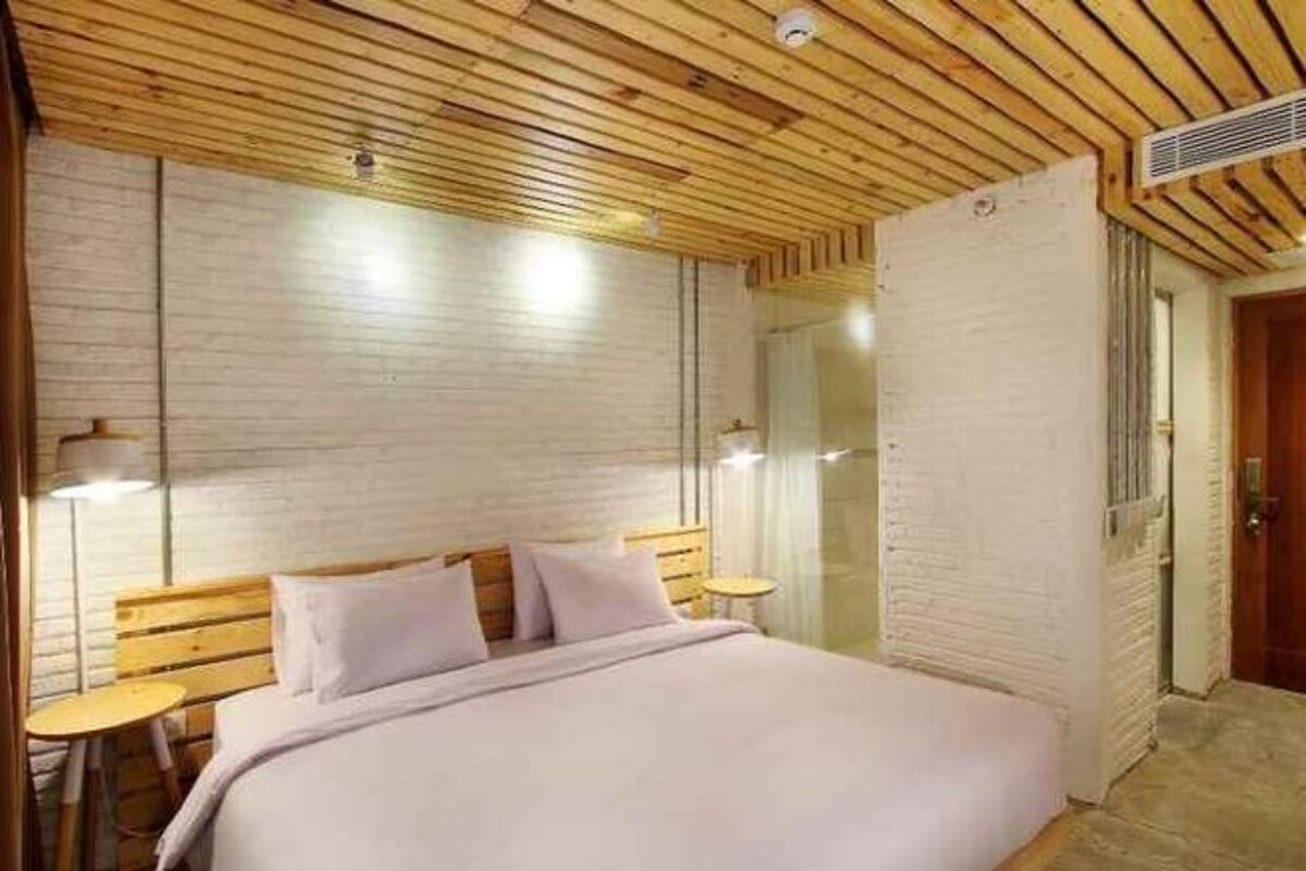 Un dormitorio con una cama, mesitas de noche y techo de madera.