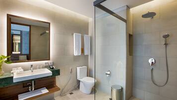 Ein modernes Badezimmer mit einer in Glas eingefassten Dusche, einem Waschbecken mit Marmorplatte und einer Toilette.