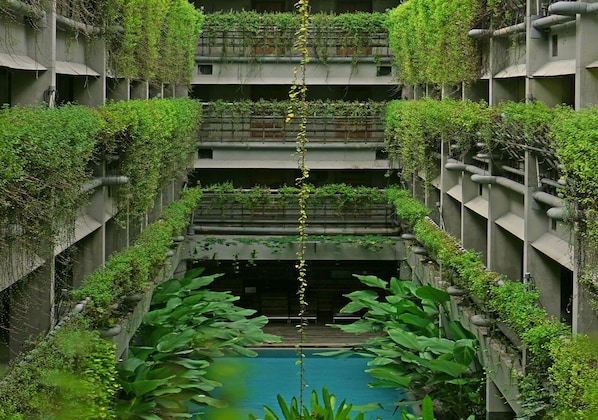 Un edificio de varios niveles con jardines verticales y una fuente central.