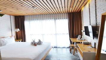 A hotel room with a large bed, a desk, a TV, and a view of the outdoors.
