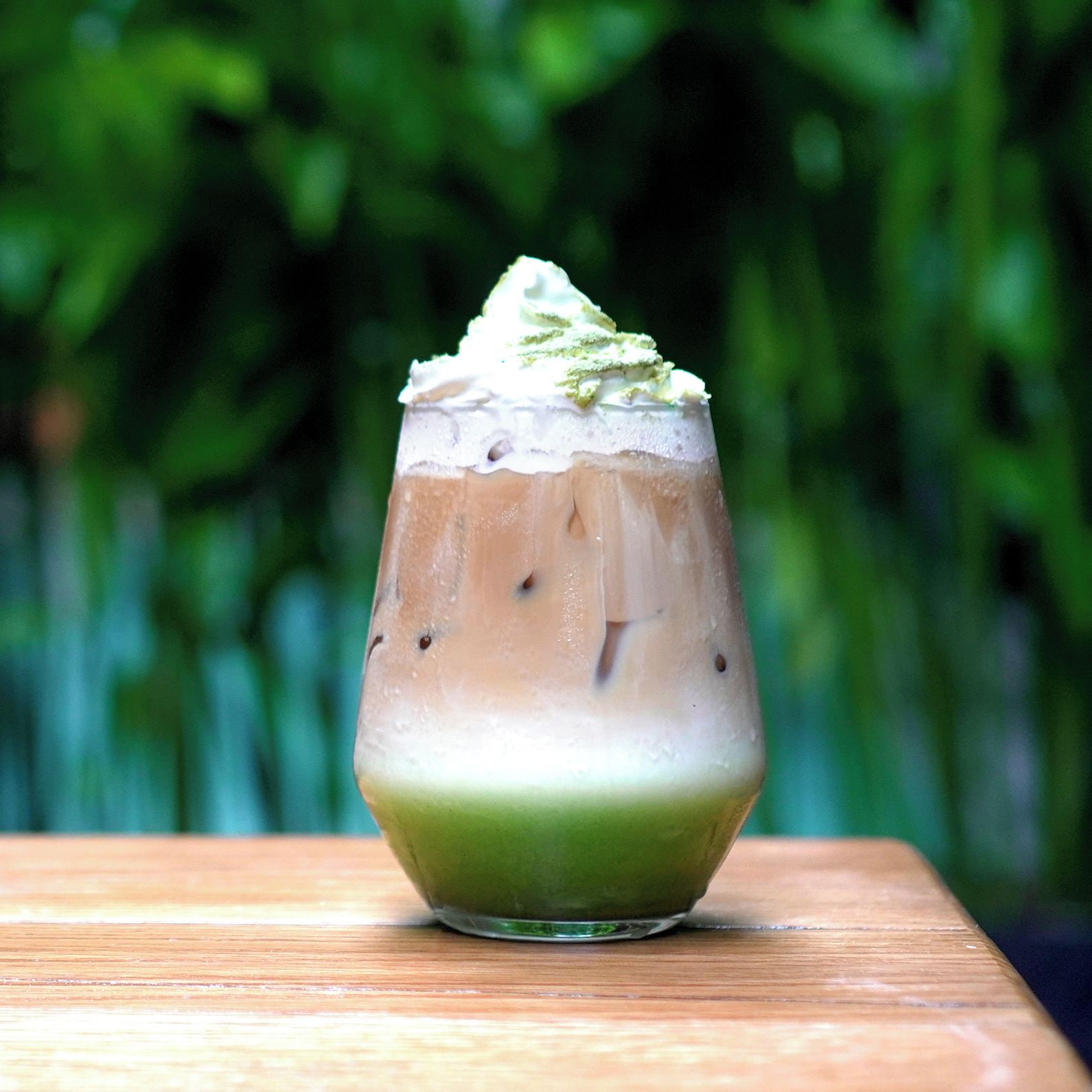Ein Eiskaffee mit Schlagsahne auf einer Holztischplatte.