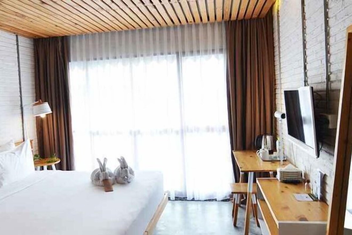 A hotel room with a bed, a desk, a television, and a window with curtains.