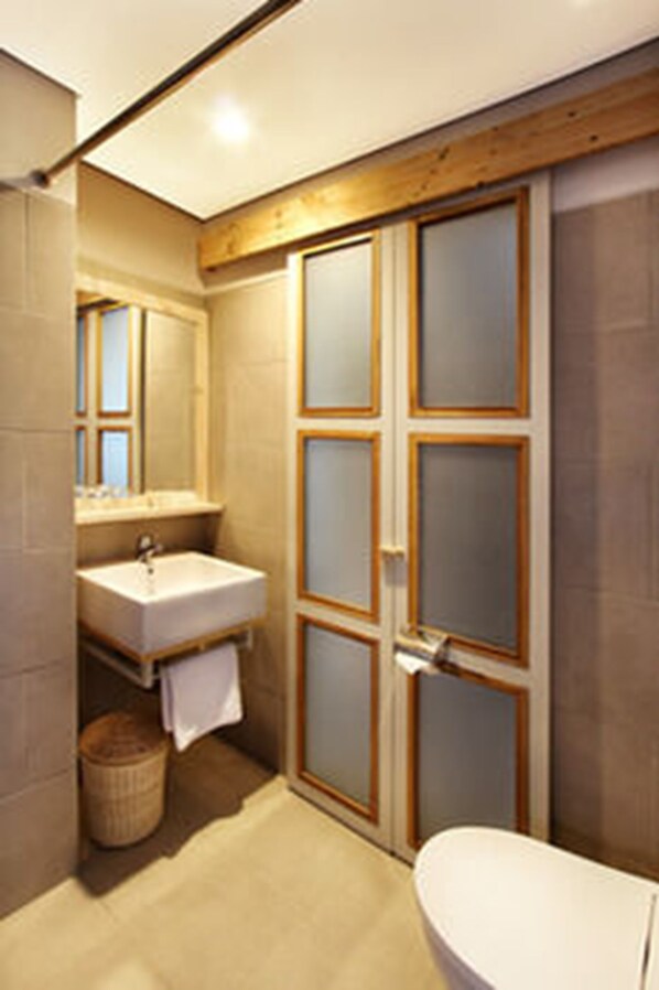 Un baño con techo de madera, un lavabo blanco, un espejo y un inodoro blanco.