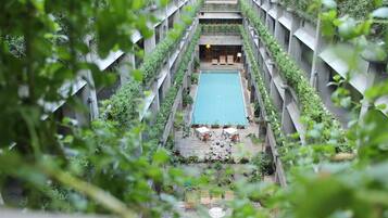 A rooftop pool with a view of the surrounding greenery and a staircase leading up to it.