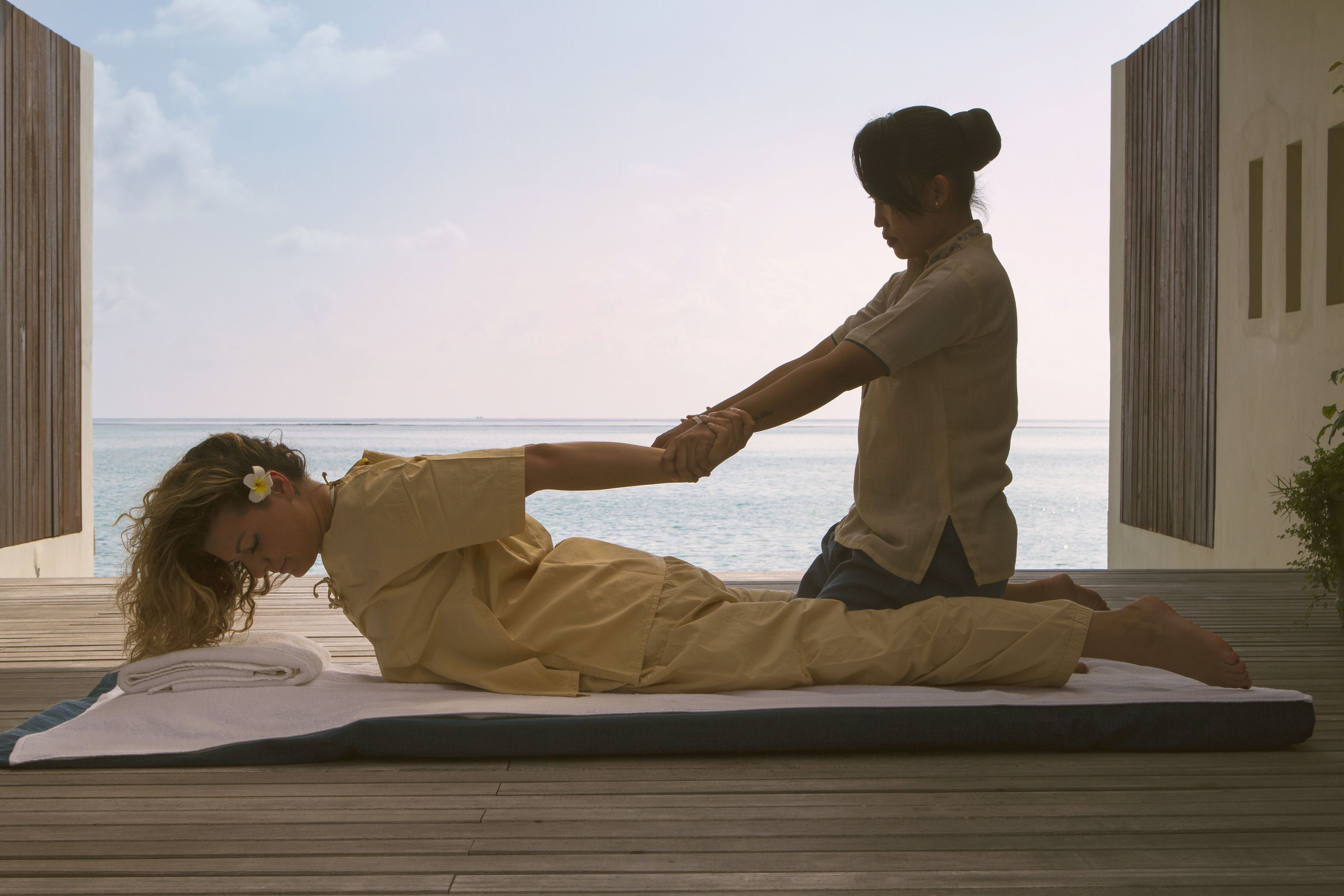A person receiving a massage on a mat with a view of the sea.