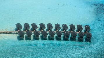 A row of overwater bungalows connected by a wooden walkway.