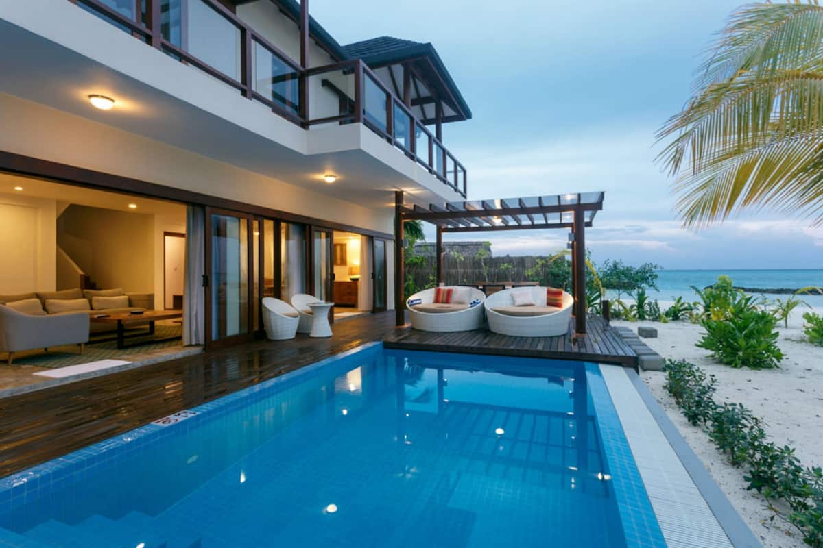 Una casa moderna con piscina, mobiliario exterior y vistas al océano.