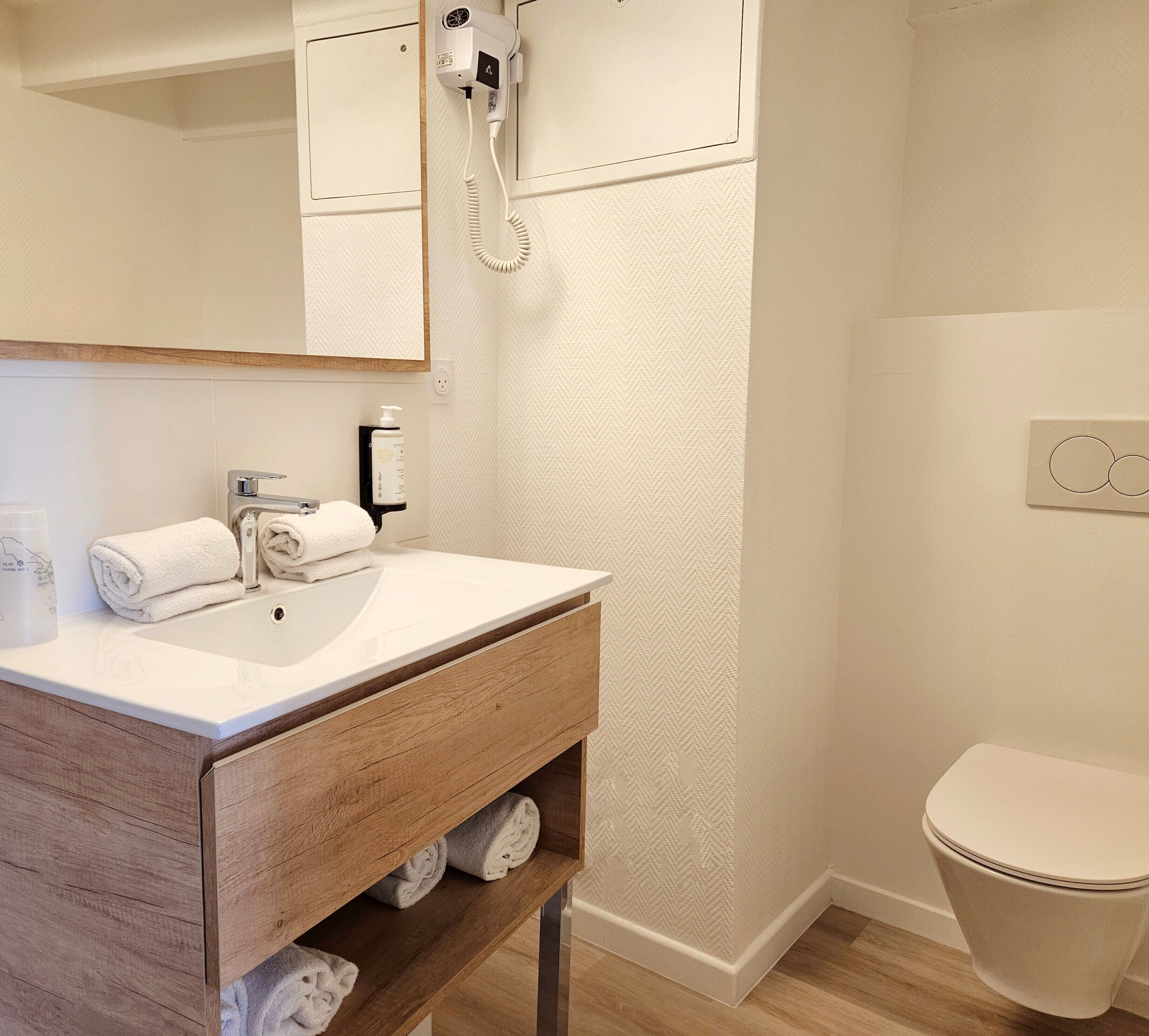 Ein Badezimmer mit einem Holzbadezimmerschrank, einem weißen Waschbecken, einem Handtuchhalter und einer Toilette.