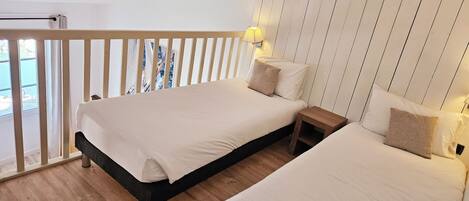 A bedroom with a bed, bedside tables, and a view through a window.