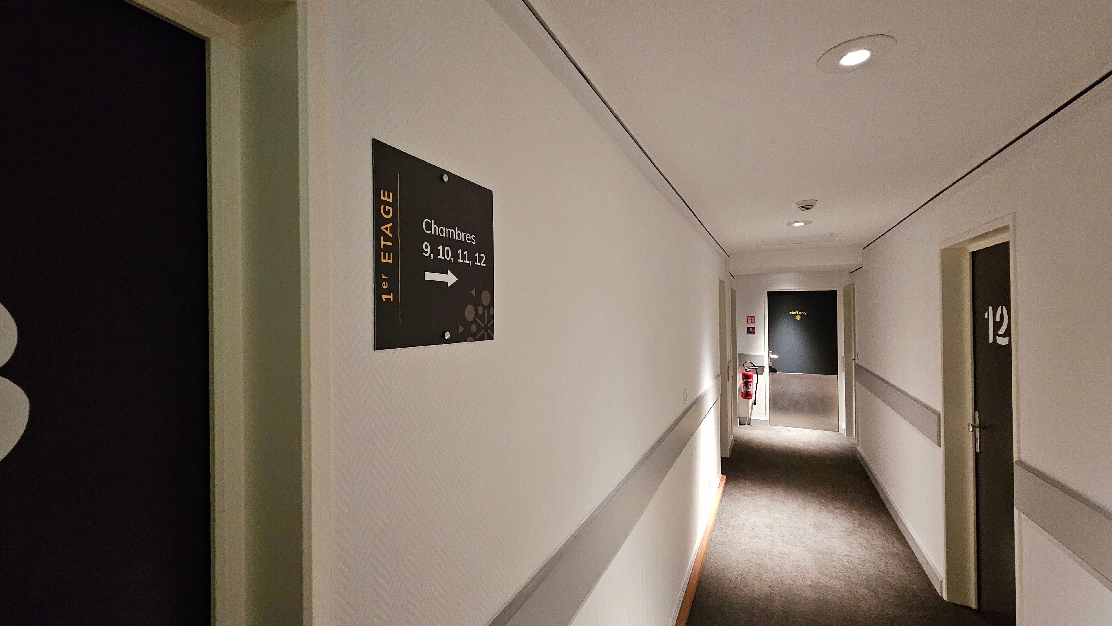 Un pasillo de hotel con un cartel que indica los números de habitación 9, 10, 11 y 12, así como una puerta para empleados.