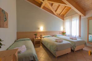 Ein Zimmer mit zwei Betten, einem Holzkopfstück, Nachttischen und einem großen Fenster mit Vorhängen.