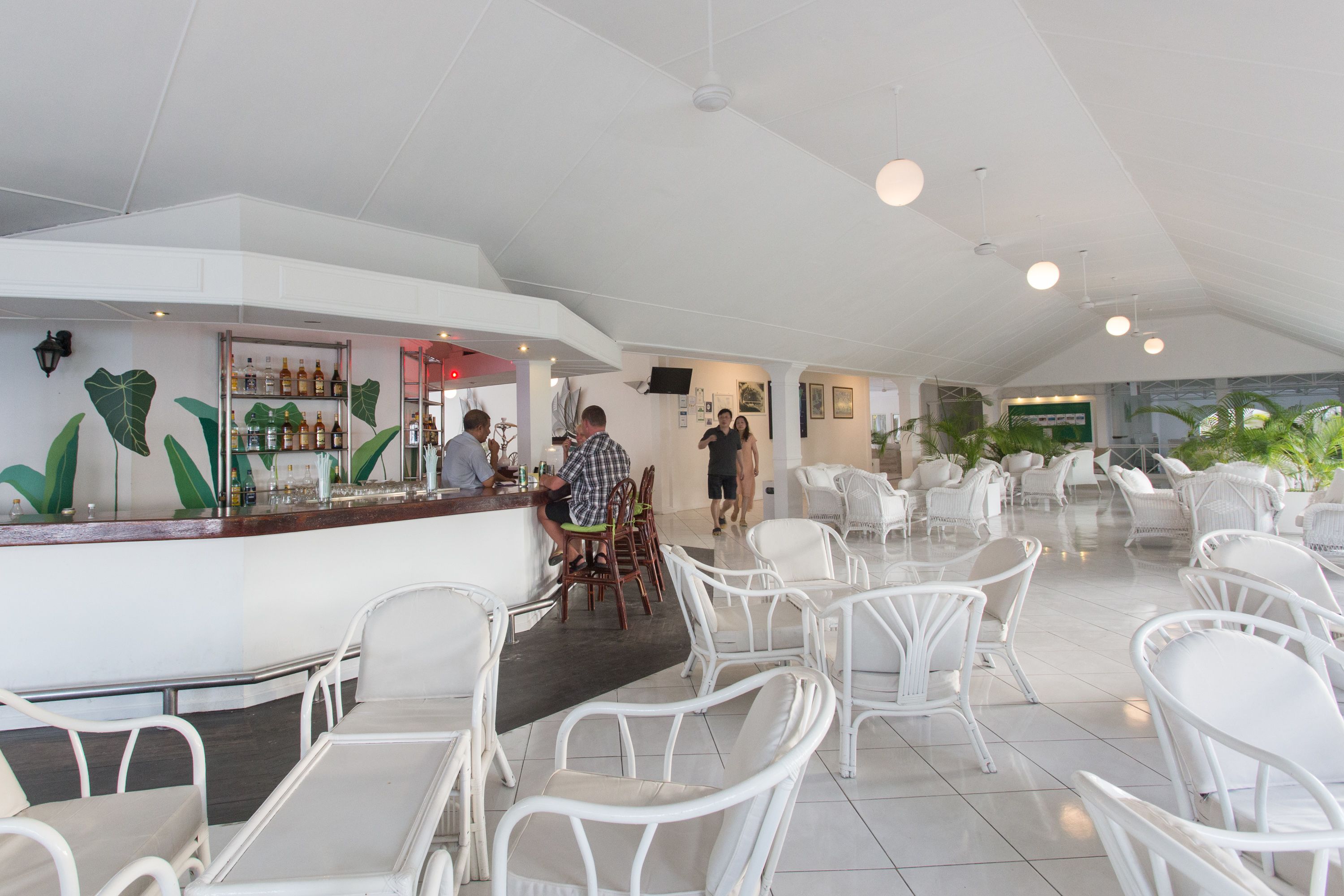 A spacious indoor area with white chairs and a bar area.