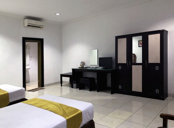 Habitación de hotel con dos camas, un escritorio con computadora, armario y aire acondicionado.
