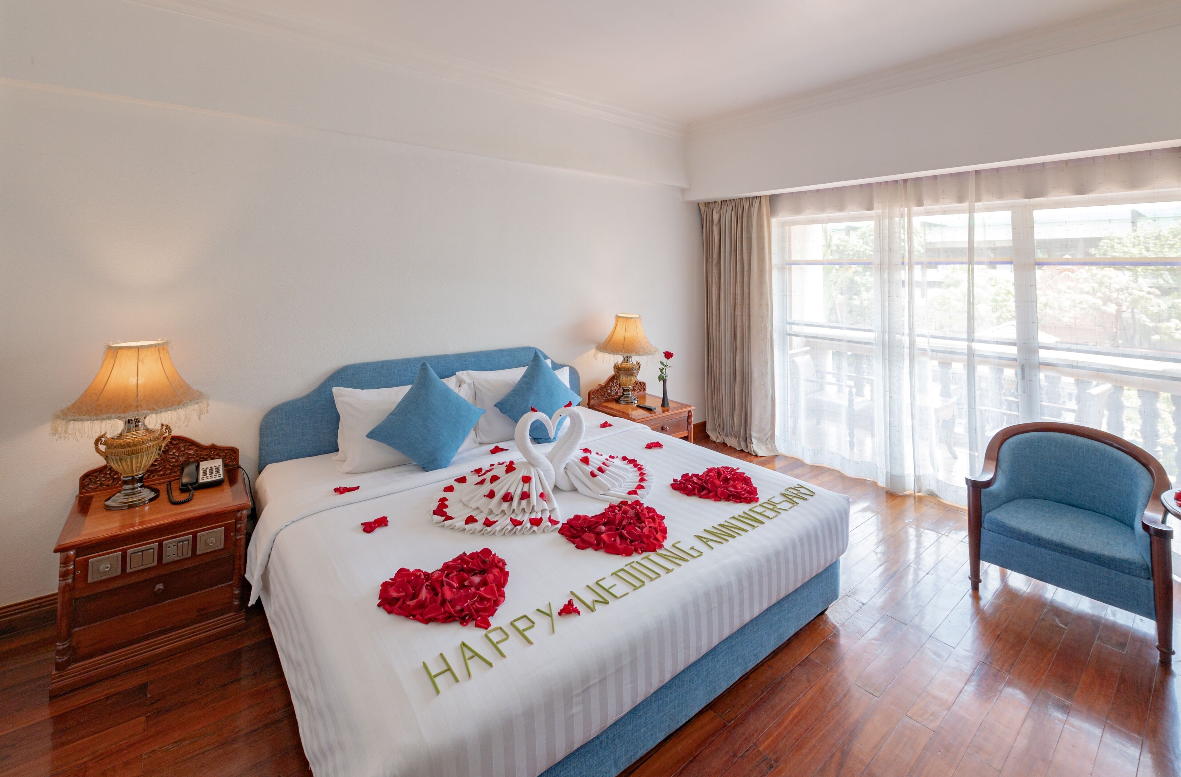 A hotel room with a bed, two bedside tables, a lamp, a chair, and a window with curtains.