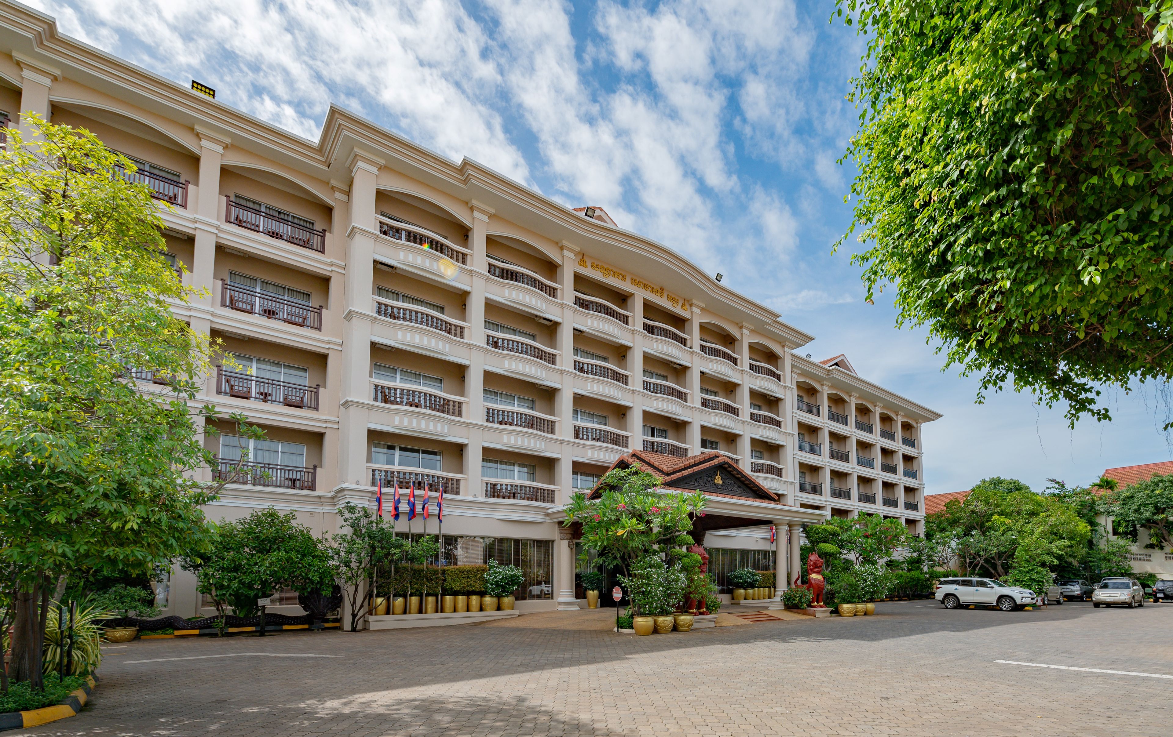 A multi-story hotel with a symmetrical facade, balconies, and a central entrance with a decorative archway.