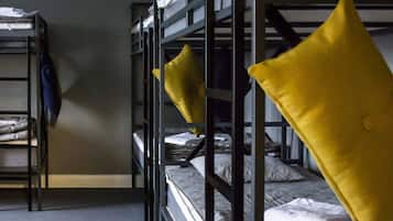 Ein Schlafsaalzimmer mit Etagenbetten, einem grauen Teppich und einer blauen Jacke an der Wand.