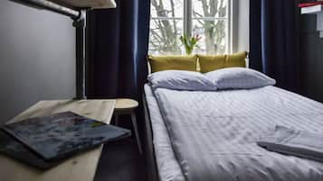 Habitación de hotel con cama, una mesita, una silla y ventana con vista a árboles.