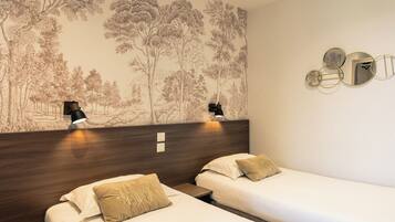Habitación de hotel con dos camas individuales, cabecero de madera, lámpara de pared y un mural decorativo con un árbol.