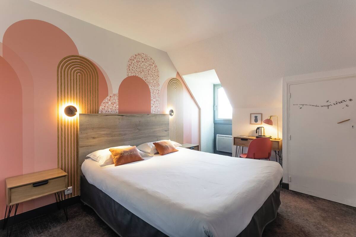 Un dormitorio con cama, mesitas de noche, un escritorio y una silla.
