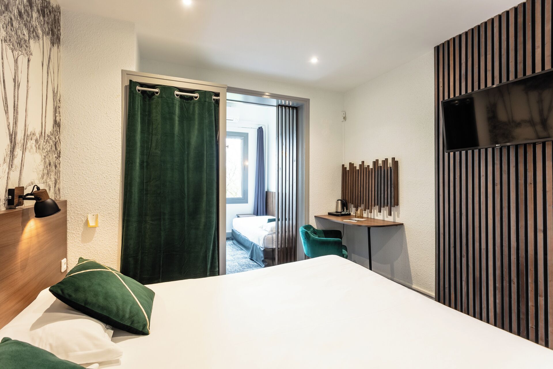 Habitación de hotel moderna con una cama grande, un escritorio con silla, televisor montado en la pared y vista al exterior.