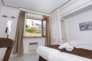A hotel room with a bed, a wooden headboard, a window with curtains, a radiator, and a painting on the wall.
