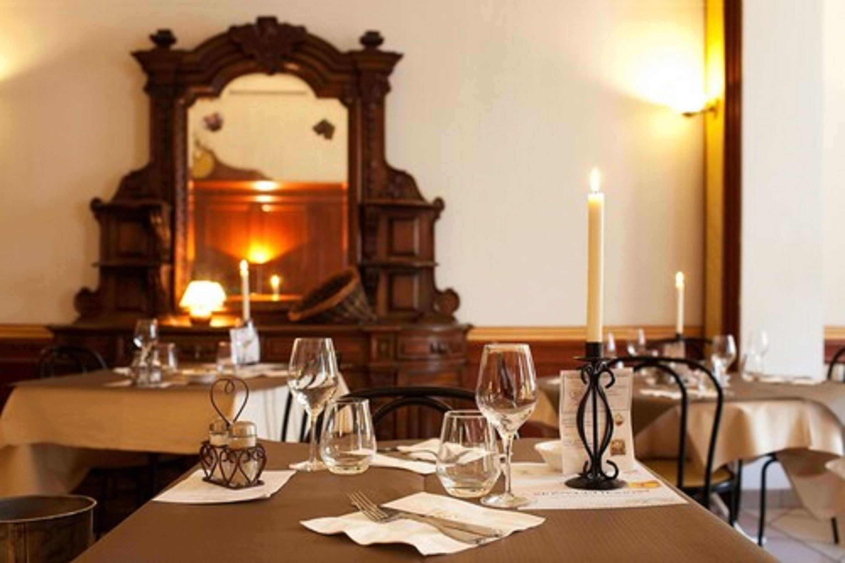 A dining table set with wine glasses, a candle, and a menu.