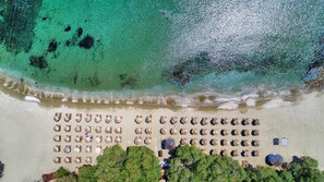 Aan het strand, wit zand, ligstoelen aan het strand, parasols