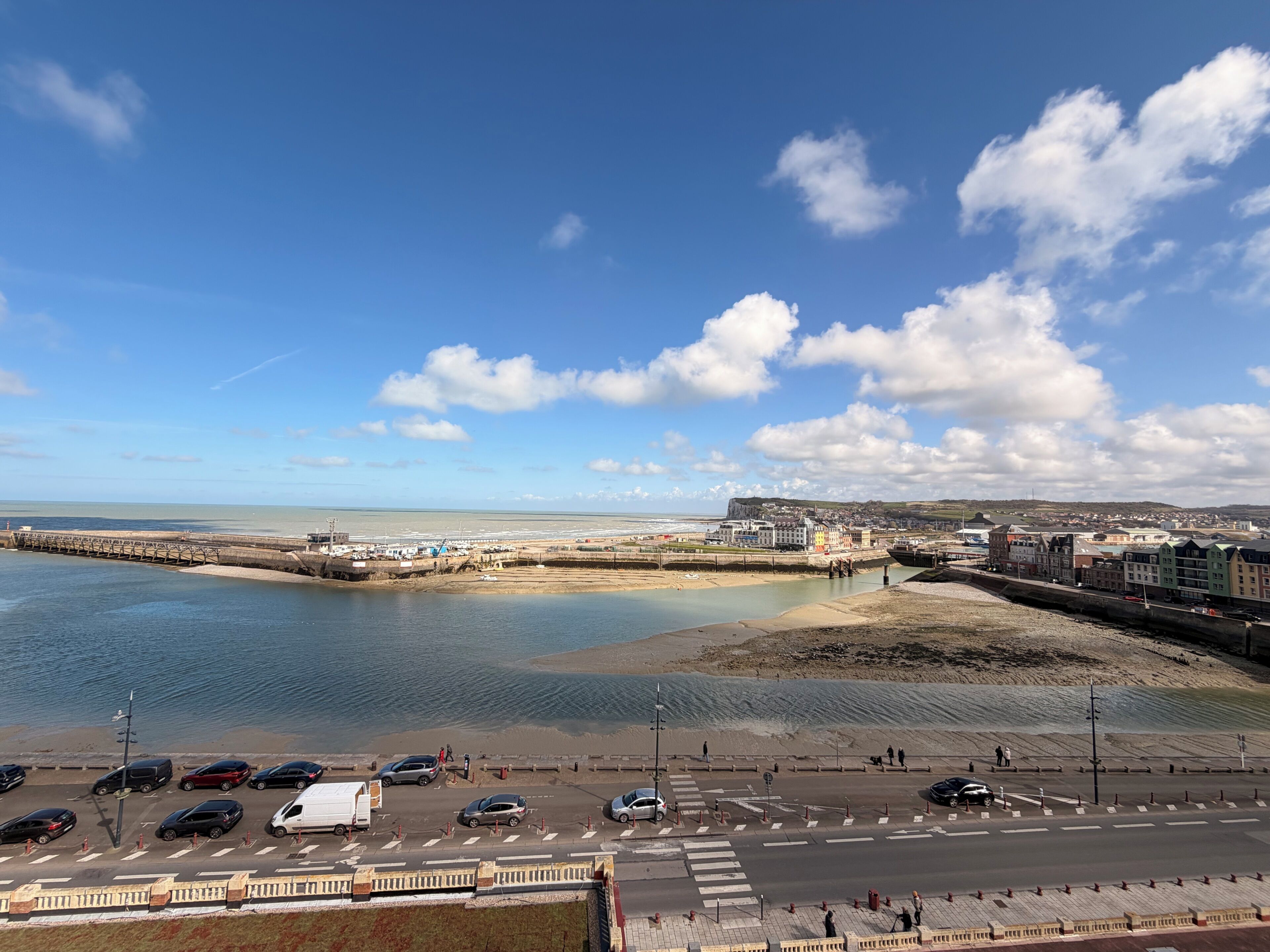 A coastal town with a beach, promenade, and a view of the sea.
