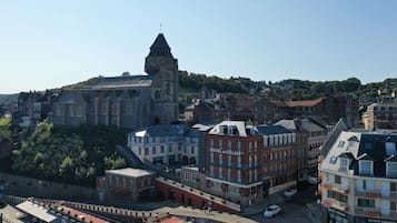 Un edificio histórico con una torre destacada, un hotel llamado 'Hotel de Calais', y una calle con coches estacionados.