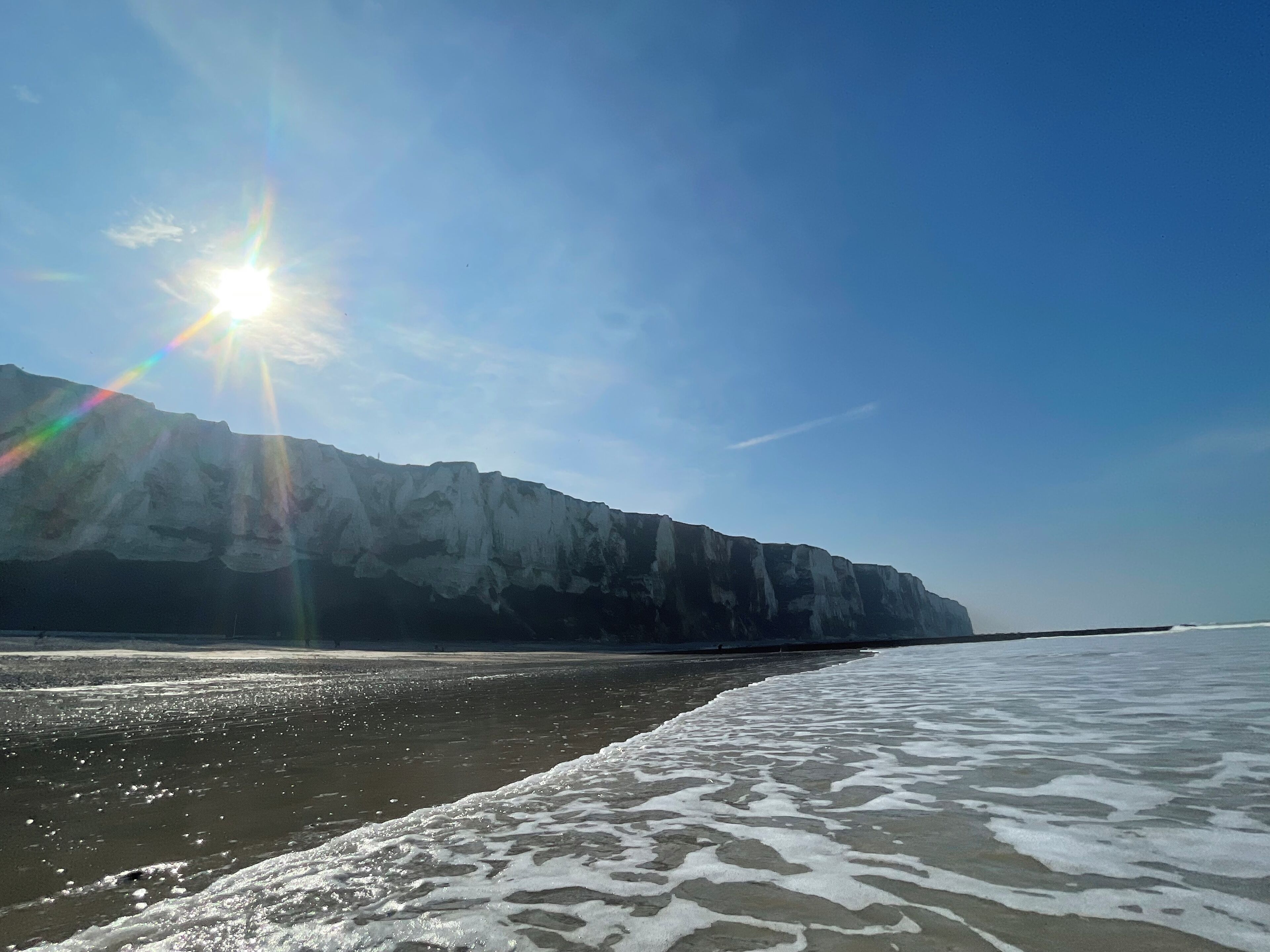A beach with a rocky cliff in the background.