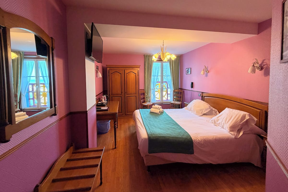A bedroom with a bed, a desk, a chair, a wardrobe, and a staircase.