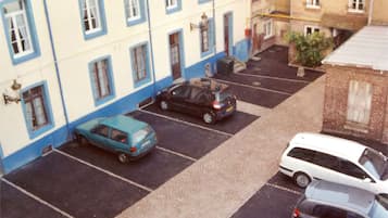 A courtyard with parked cars and buildings with traditional architecture.