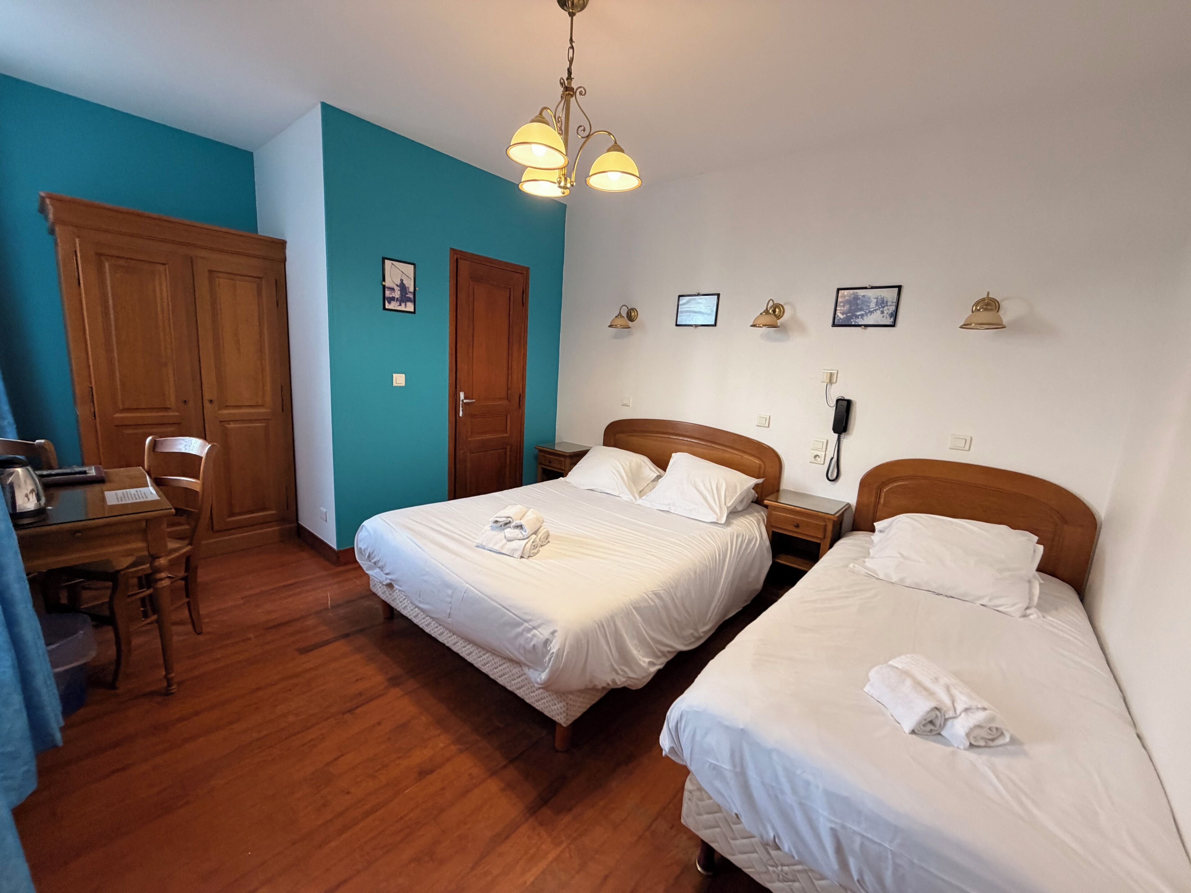 Une chambre d’hôtel avec deux lits, un bureau, une chaise, une armoire et un téléphone.