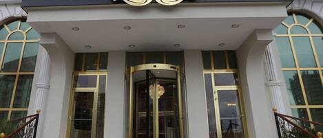 Exterior del hotel Reis Inn Istanbul, con una entrada imponente, amplias puertas de vidrio y una escalera que conduce a la entrada.