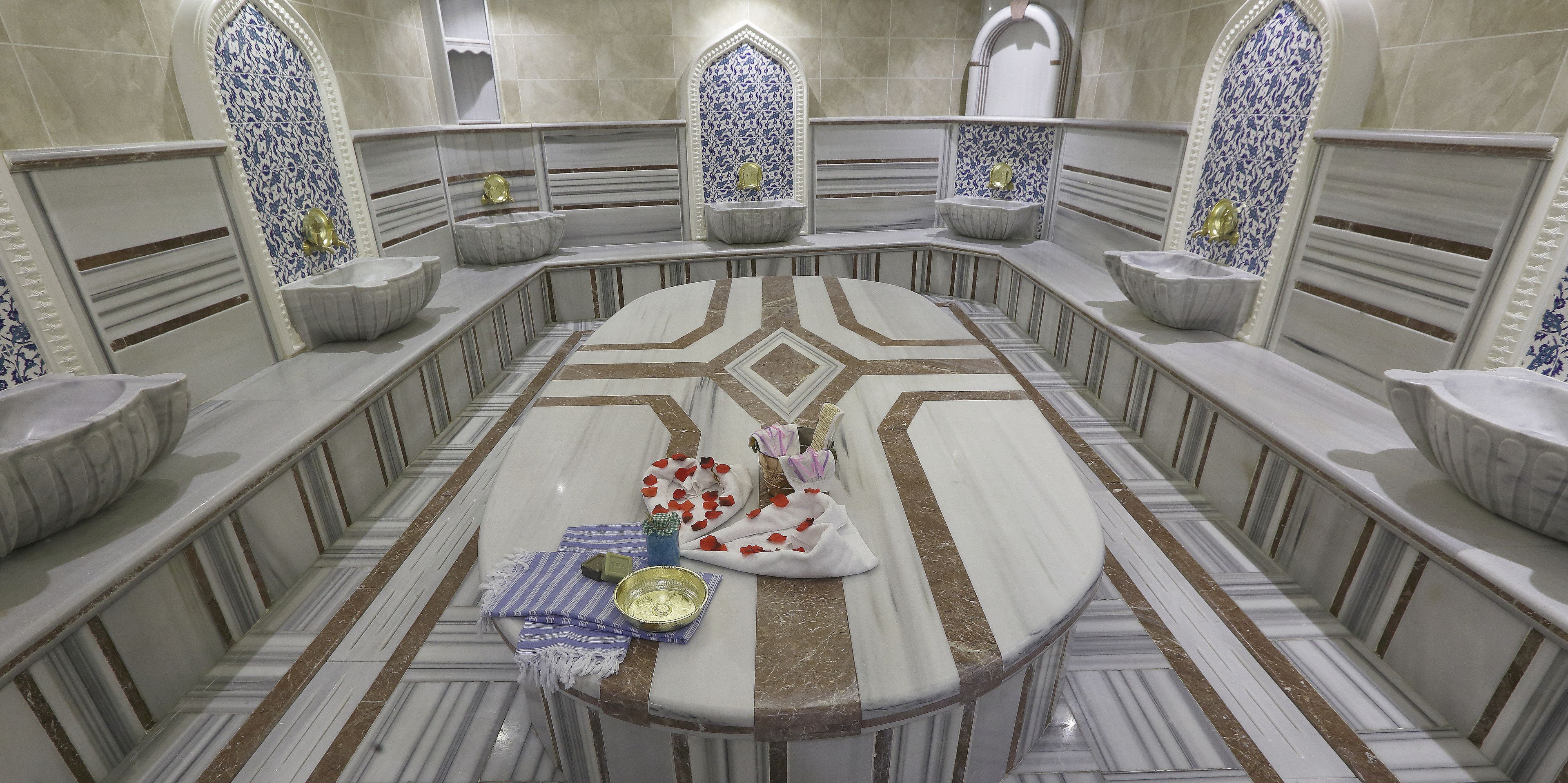 A luxurious bathroom with a central marble sink, multiple smaller sinks, and a decorative mirror.