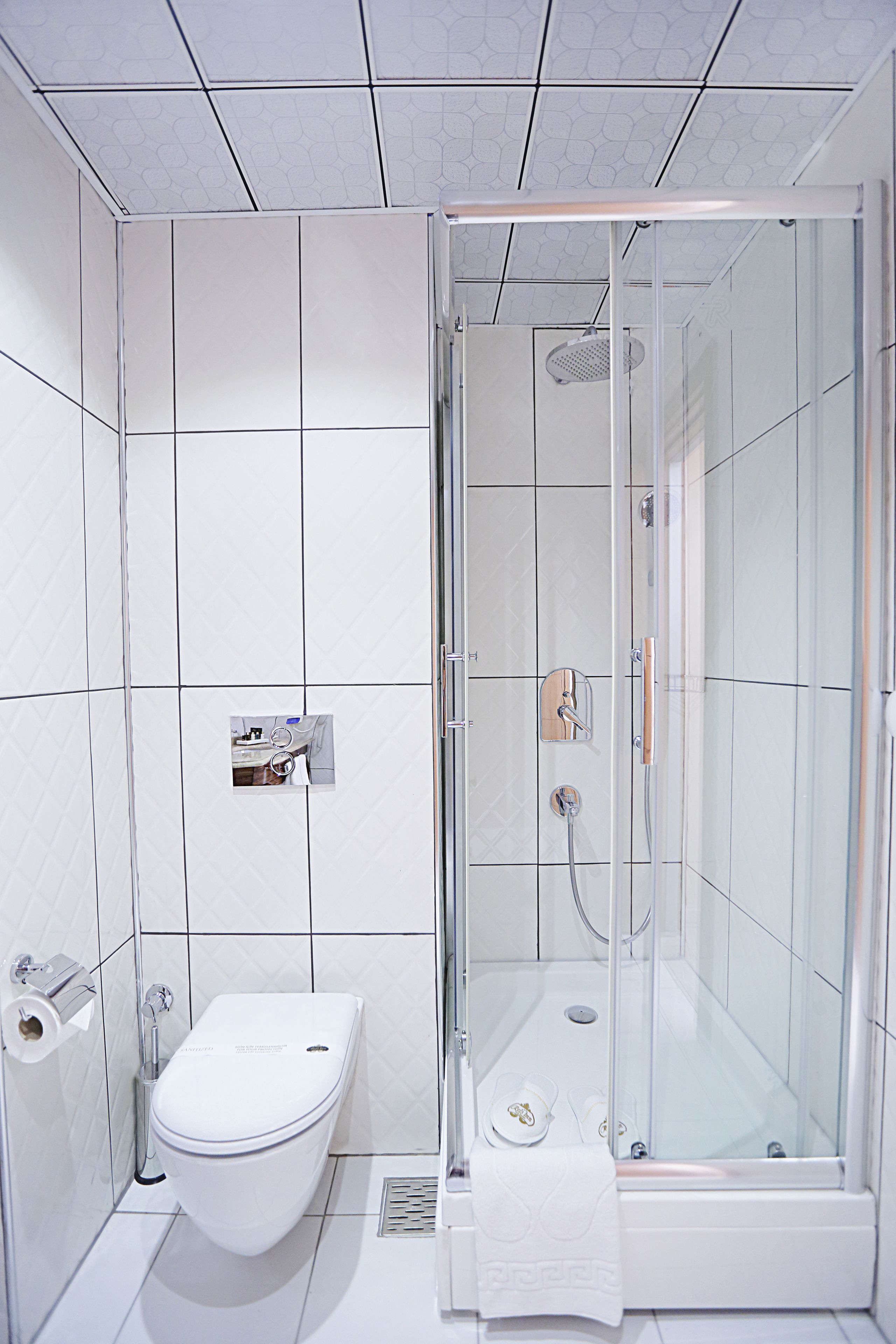 A modern bathroom with a toilet, a shower with a glass door, and a towel rack.