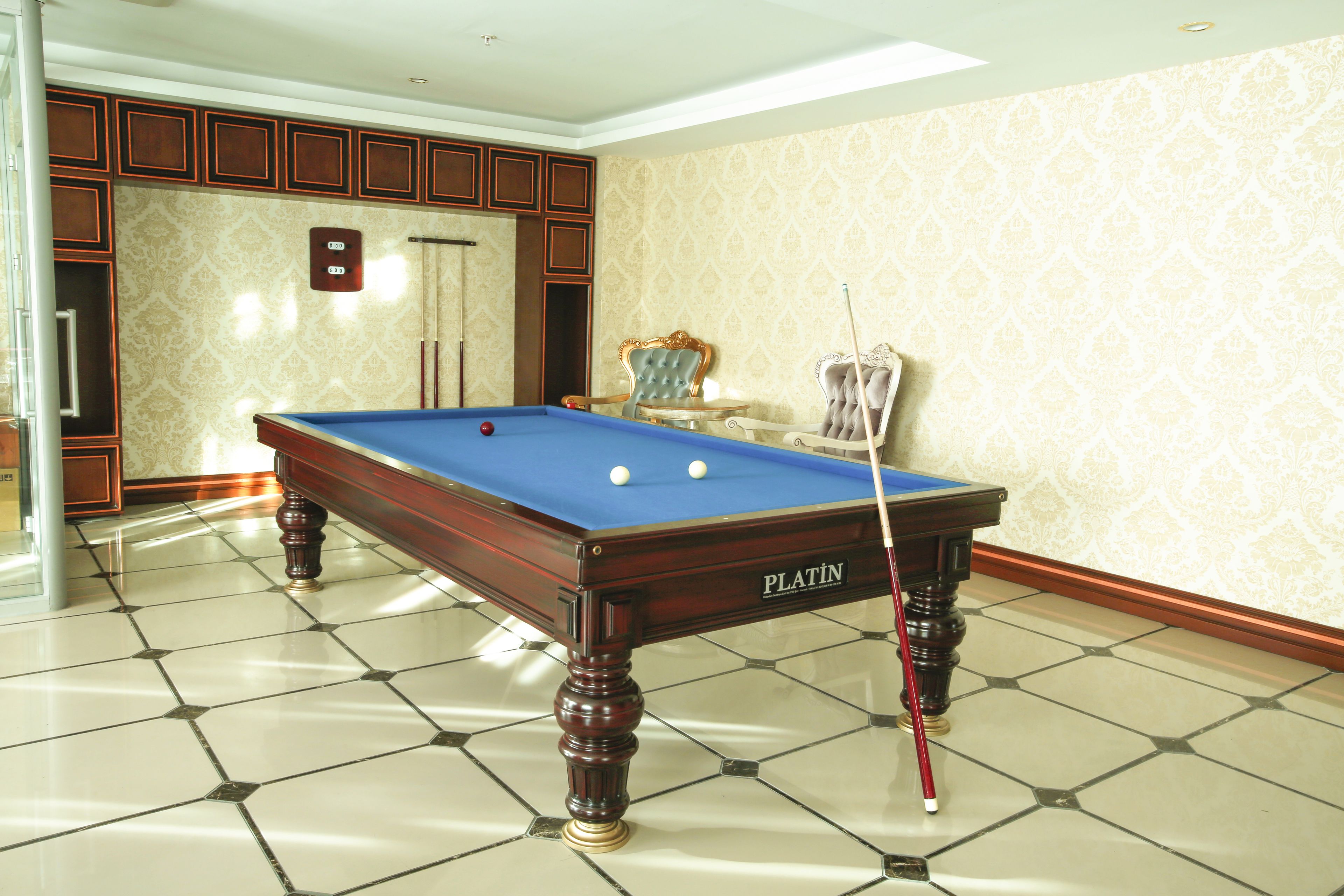 Een pooltafel met een blauwe viltkleed, een poolkeu en een biljartbal.