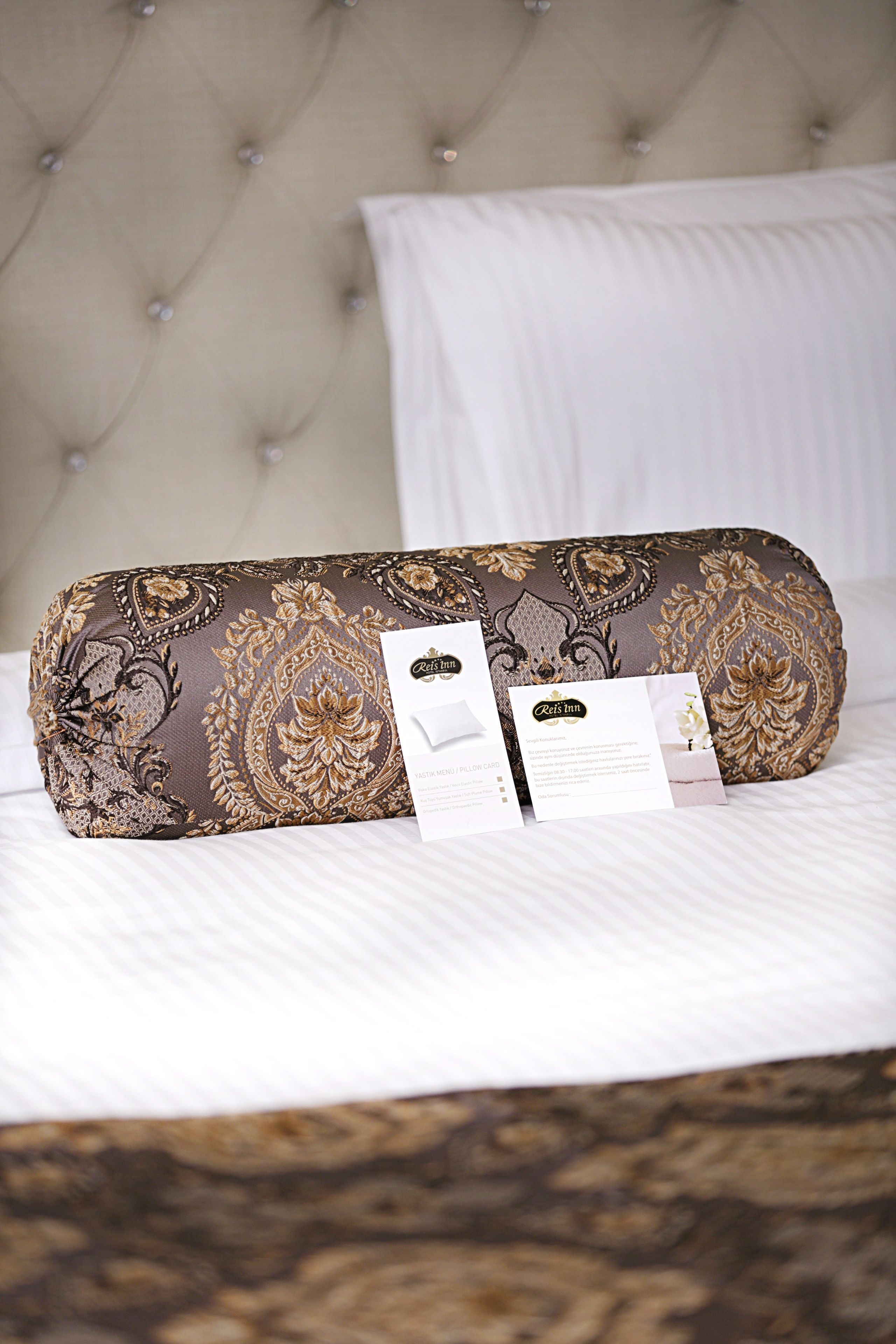 A bed with a tufted headboard, a decorative pillow, and two informational cards.