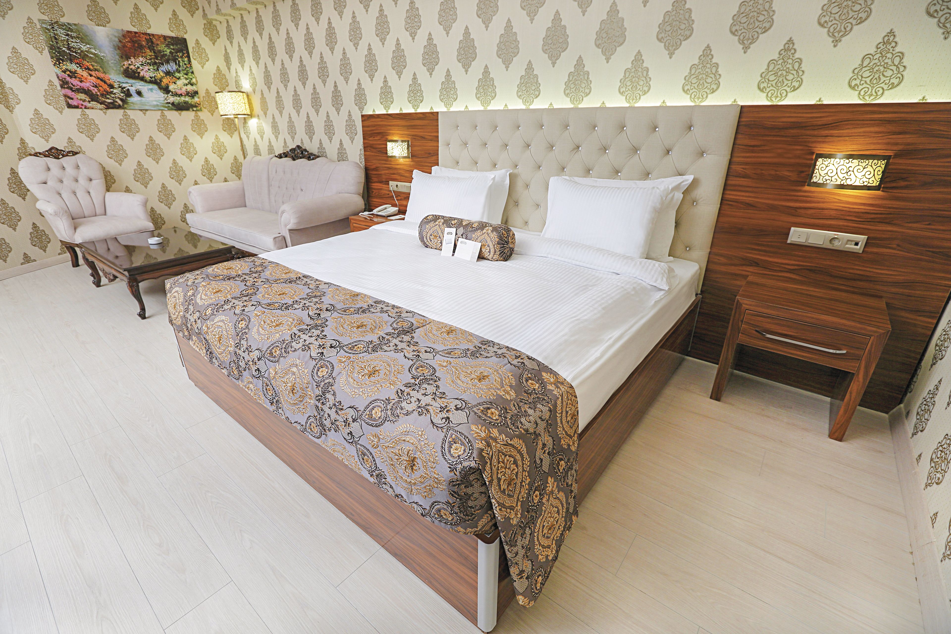 Ein Hotelzimmer mit einem großen Bett, einem Nachttisch, einem Sessel und einem Schlafsofa.