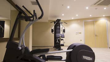 Un gimnasio con equipo de ejercicio, un espejo y una puerta al fondo.