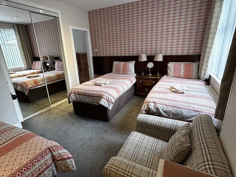 Quarto de hotel com duas camas, um sofá, um espelho e um armário.