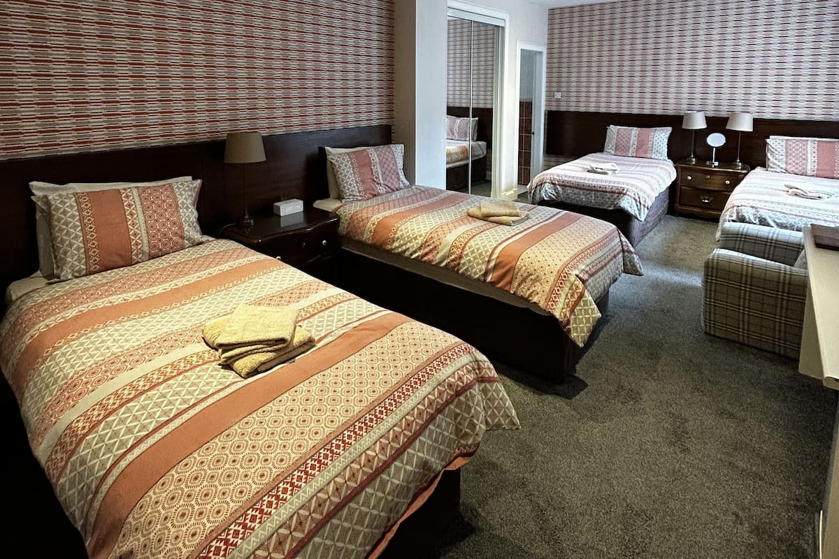 A hotel room with two beds, a small seating area, and a mirror.
