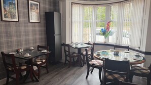 Een eetgedeelte met een erker, kunstwerken aan de muur en een koelkast.
