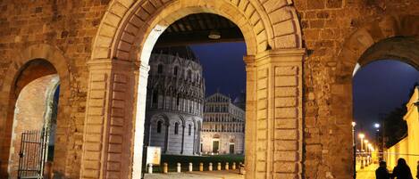 An arched stone structure with a view of a historic building in the background.